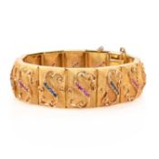 A RUBY AND SAPPHIRE-SET GOLD BRACELET, each rectangular panel decorated with textured gold scrolls