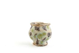 A TIN GLAZED OINTMENT POT 17TH CENTURY of footed ovoid form, with manganese and yellow-green spotted