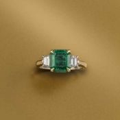 AN EMERALD AND DIAMOND THREE STONE RING