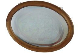 An Edwardian oval wall mirror with bevelled edge plate and moulded pine surround, 62 cm high x 87