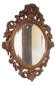 A 19th century oval wall mirror with bevelled edge plate set within a walnut frame with carved