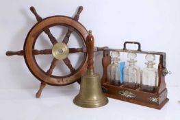A three bottle tantalus, a ships wheel and a bell, 20th century,