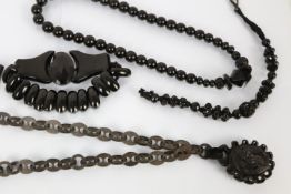 A collection of jet and jet coloured jewellery to include bead panels, a carved pendant and