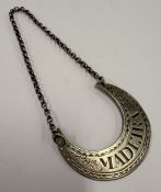 A crescent-shaped 18th Century silver wine label.