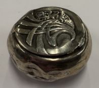 A chased silver pill box.