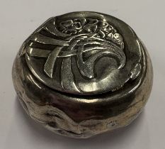 A chased silver pill box.