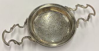 An oversized George III silver lemon strainer.