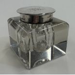 A silver-lidded glass inkwell.