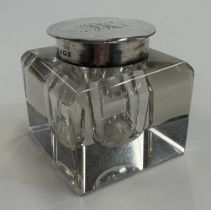 A silver-lidded glass inkwell.