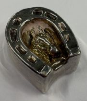 A silver model of a horseshoe with embossed decoration of horse to centre. Approx. 14 grams. Est. £