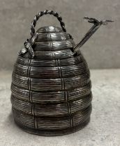 A silver honey pot with lift-off cover and glass liner in the form of a beehive.