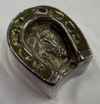 A silver model of a horseshoe with embossed decoration of horse to centre. Approx. 13 grams. Est. £