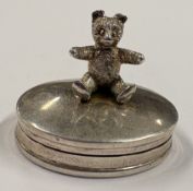 A silver pill box with hinged cover mounted with a teddy bear. Approx. 11 grams. Est. £40 - £60.