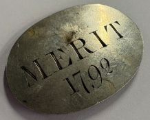 An 18th Century medallion inscribed 'Merit 1792'.
