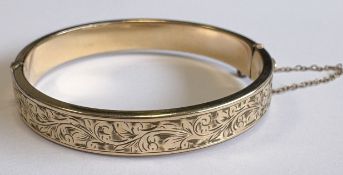 A gold-plated bangle with engraved decoration.