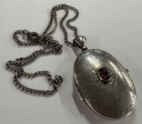 A silver locket decorated with garnet to centre on