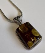 A silver-mounted necklace with amber pendant.