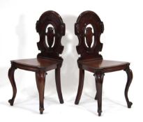 A pair of Victorian mahogany hall chairs with solid seats and turned cabriole front legs