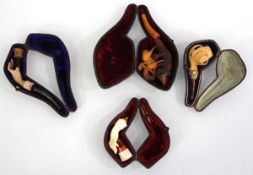 A group of cased pipes including three meerschaum and amber examples modelled as hands and a claw,