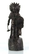 A 20th century bronze figure modelled as a standing Native American on a naturalistic base,