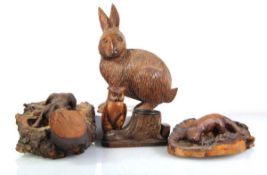A group of four treen carvings including an otter on a naturalistic setting, a fox, hare and an