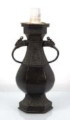 A brown-patinated spelter table lamp base decorated in the Chinese manner with character marks and