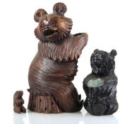A Black Forest style carved wooden bottle holder, together with a similar candle holder and a