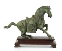 A 20th century green-patinated bronze sculpture modelled as a Tang-dynasty horse, on a stepped
