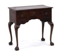 A George III mahogany and crossbanded lowboy, the shaped apron with three drawers, on cabriole