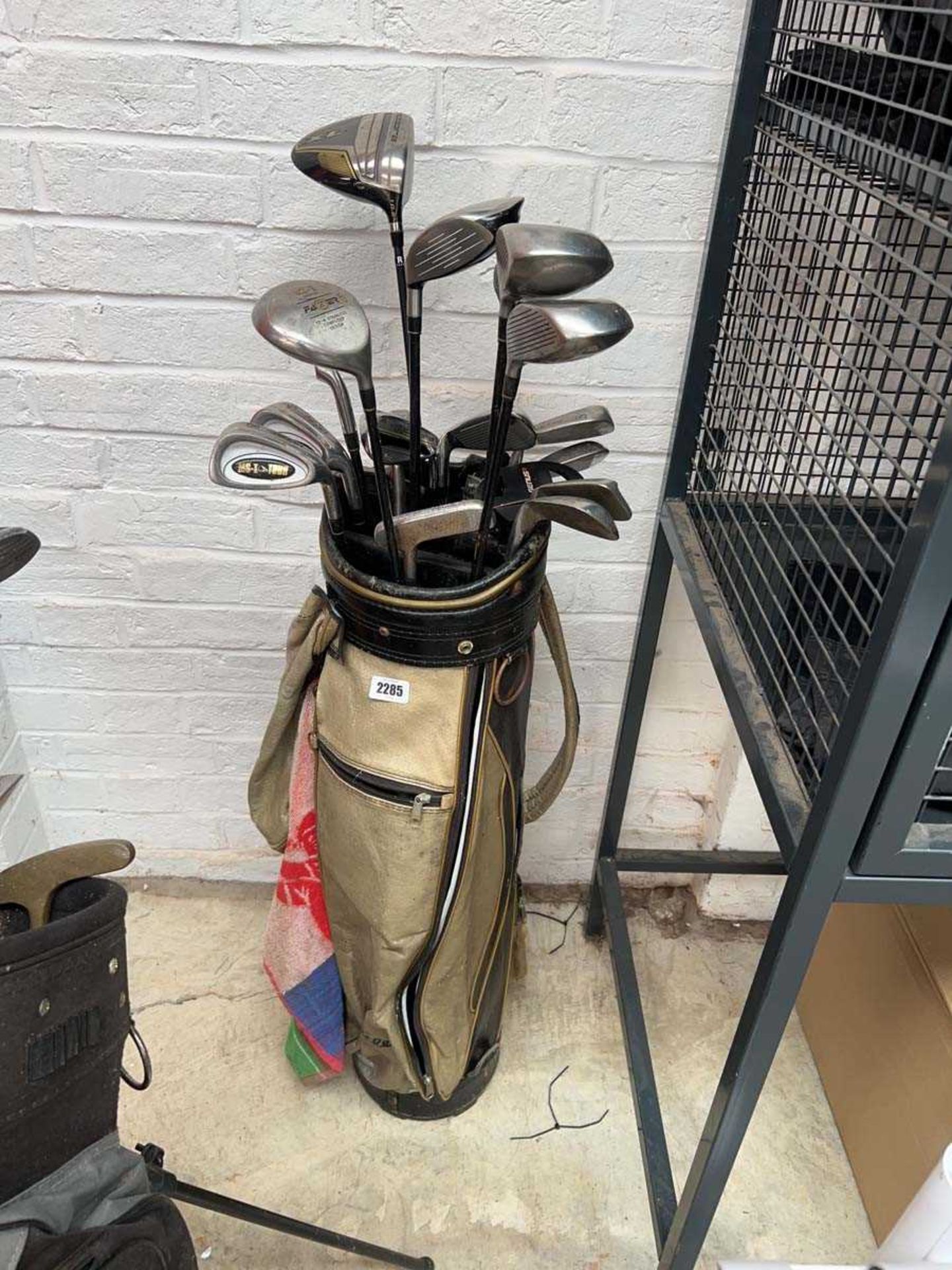 Gold and black golf bag containing a quantity of mix branded golf clubs to include Cobra XL