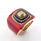A luxurious gold ring featuring red laser enamel, elegantly adorned with brilliant diamonds. -