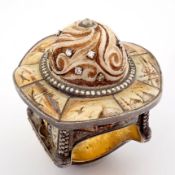 An exquisite gold/silver ring intricately detailed with a bone - carved center .surrounded by