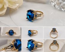 Title: Blue Oval Stone Statement Ring – 16x13mm Centre Stone Description: Elegant gold-tone
