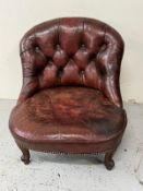 An oxblood leather library low armchair with button back. Height 68cm