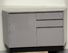 A contemporary grey laminate sideboard comprising of three graduated drawers flanked by a single