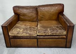 A distressed two seater brown leather sofa with stud detailing H 78cm x D 89cm x W 144cm
