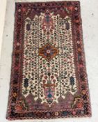 A hand made wool rug with beige grounds and red border 130cm x 80cm Condition Report general wear