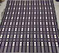 A Welsh wool rug in an Aztec style purple and white pattern. 240x230