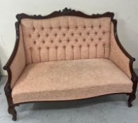 A Victorian button back two seater sofa in a peach fabric with carving to back and front (L140cm x