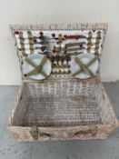 A wicker four person picnic hamper and set with plates, cups etc