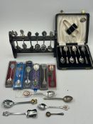 A collection of decorative spoons on a rack and boxed