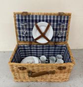 A wicker picnic hamper and set with plates, cups etc