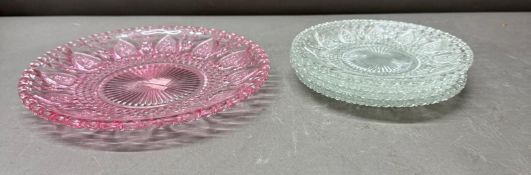 Four clear glass side plates together with a pink glass plate