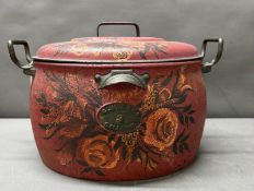 A cast iron lidded decorative cauldron, red grounds and with floral design