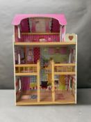 A Dolls House with pink roof and multiple colourful rooms.