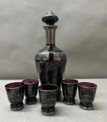 An amethyst glass decanter and five shot glasses with intricate silver overlay