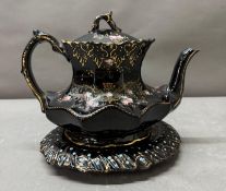 A black gilt florally painted tea pot and stand