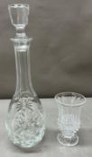 A glass decanter with a small glass vase