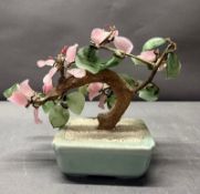 An ornamental pink glass bonsai tree in a celadon planter