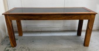 A glass-topped hardwood dining table with wrought iron decorative inserts H76cm W180cm D71cm